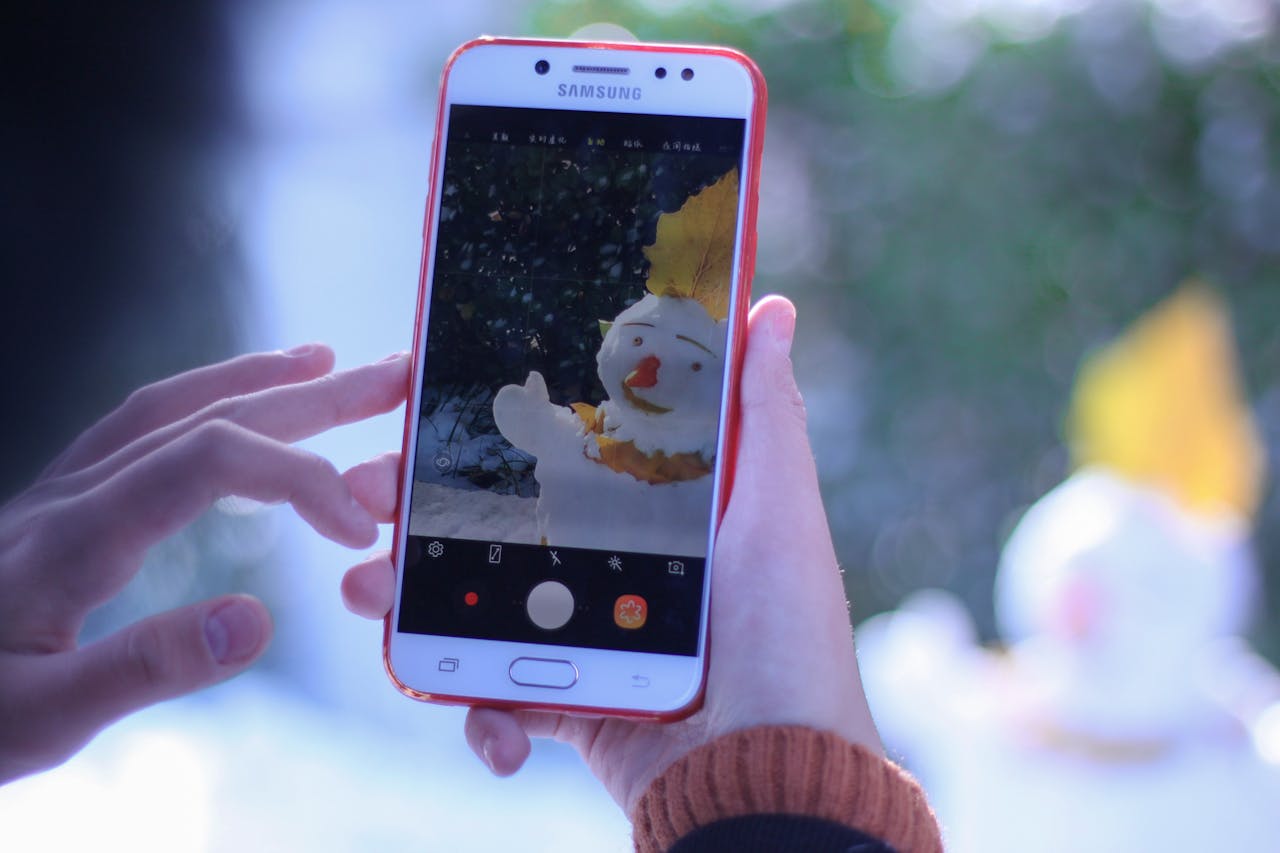 A smartphone captures an artistic photo of a snowman during winter.